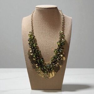 Gold tone bib necklace with gold tone metal accents and green crystal beads